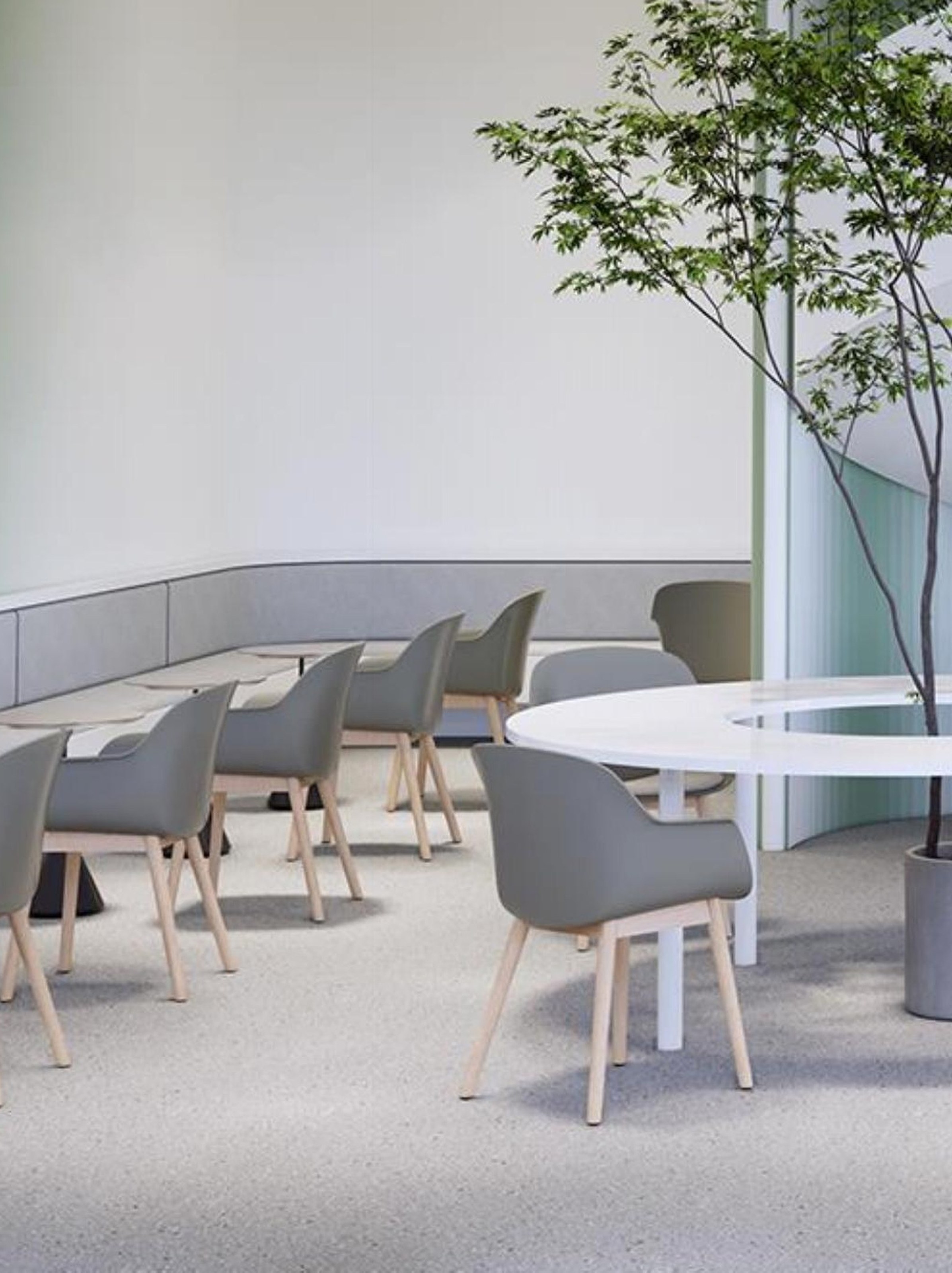 Grey tub chairs around a white café table beside a planted courtyard