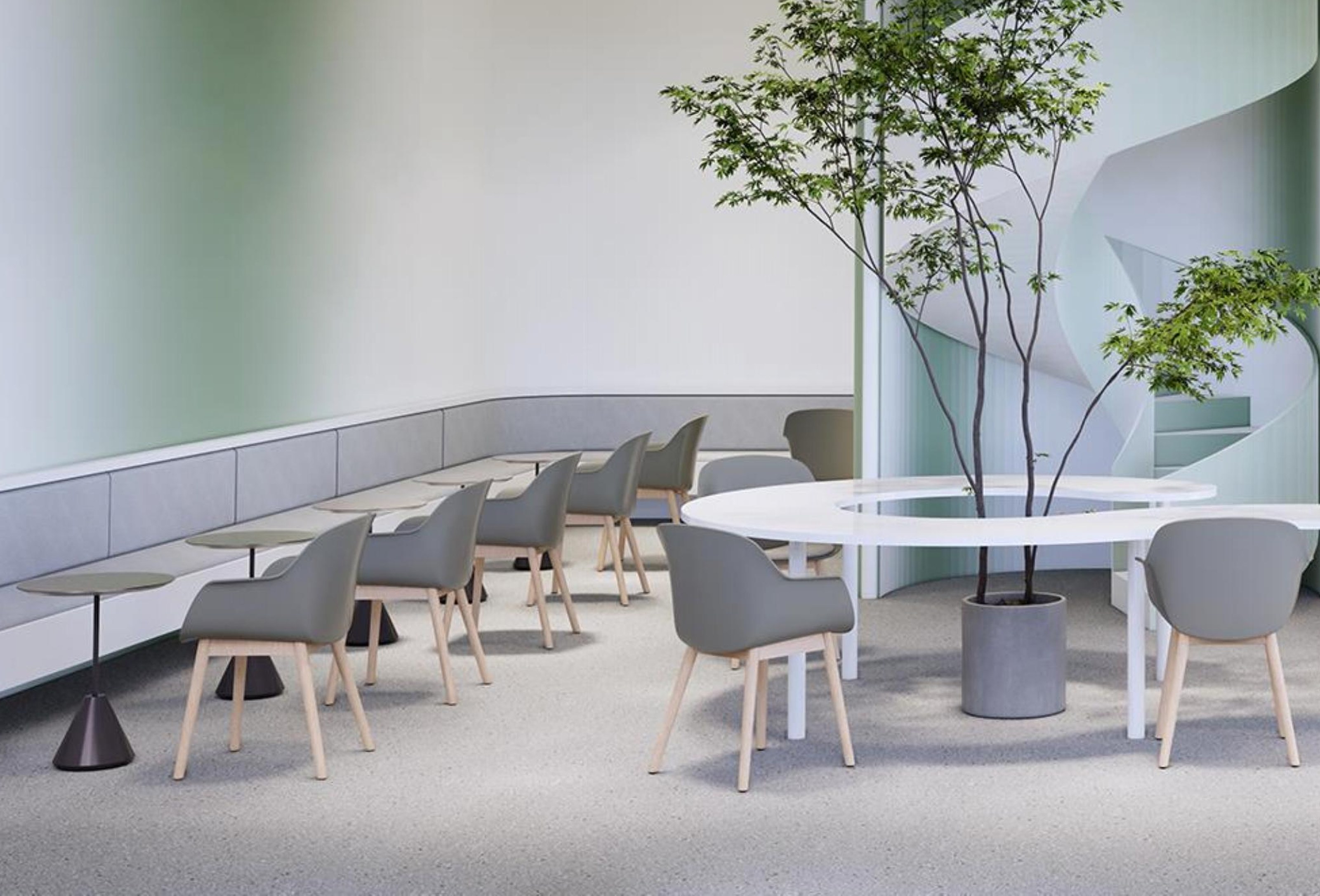 Café-style breakout seating around a planted table under a spiral stair